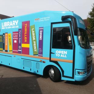 blue mobile library van with books along the side